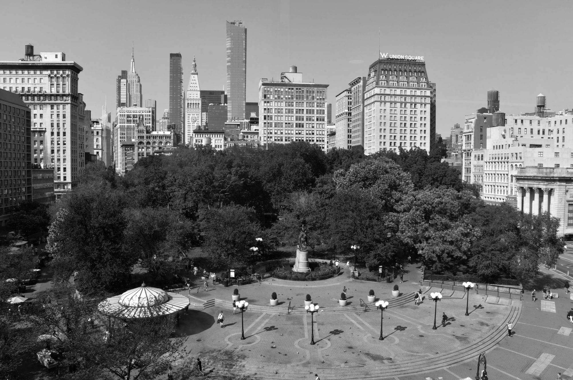 A city park with people relaxing and tall buildings in the background.